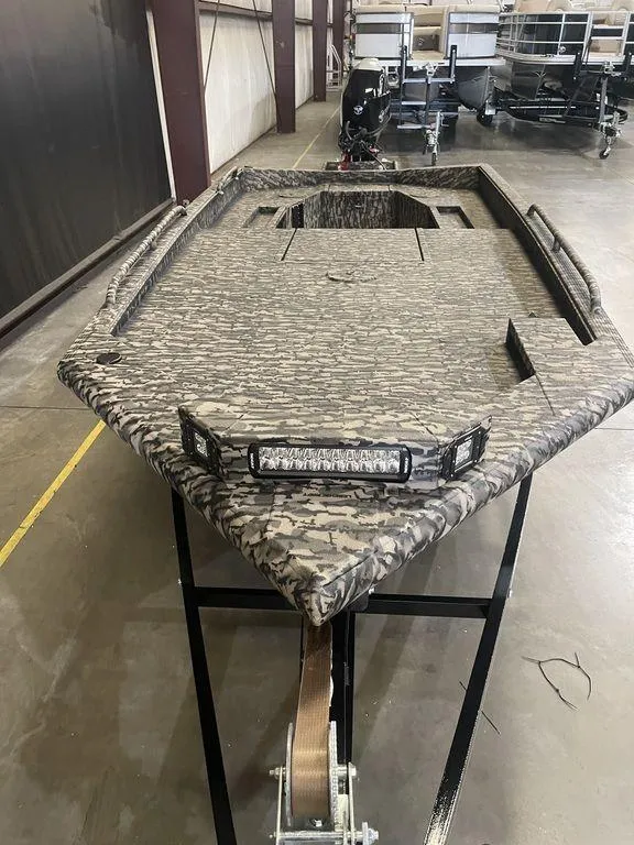 Slide: The Image of 2023 Legend Craft Outlaw 1656 boat with camouflage design in a warehouse. - 3