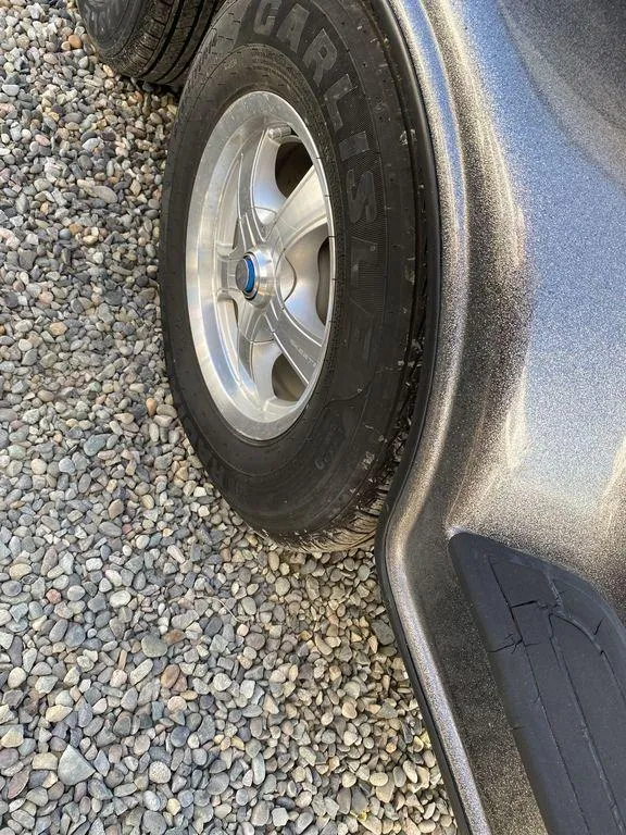 Slide: The Image of Close-up of a 2006 Skeeter Bass Boat trailer wheel on gravel. - 10