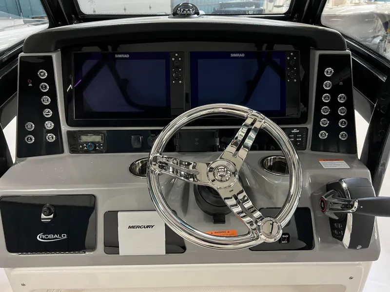 Slide: The Image of 2023 Robalo 266 Cayman boat dashboard with dual Simrad displays and Mercury controls. - 10