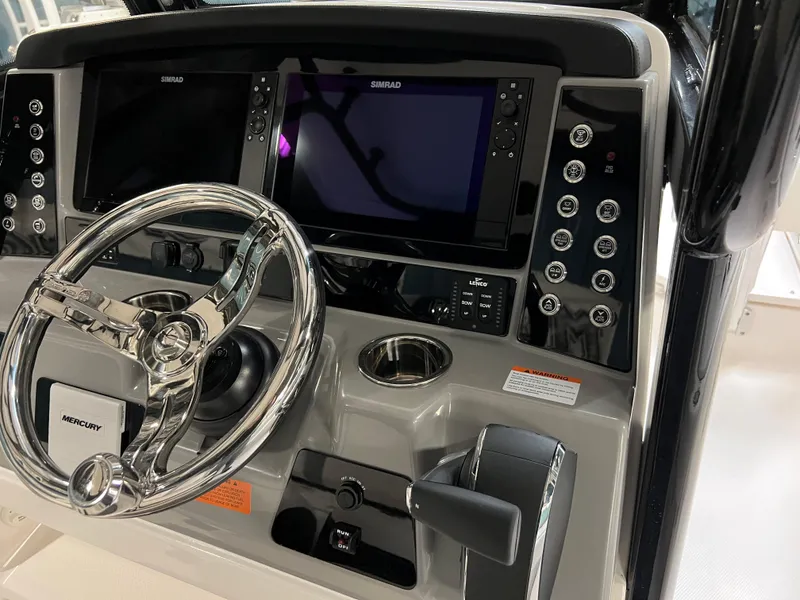 Slide: The Image of 2023 Robalo 266 Cayman boat dashboard with steering wheel and navigation screens. - 11