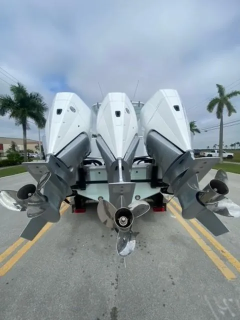 Slide: The Image of 2025 Contender 35 ST boat with triple outboard engines, parked on a palm-lined street. - 1