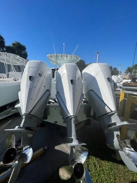 Slide: The Image of 2025 Contender 35 ST boat with triple outboard engines, docked under clear blue sky. - 9