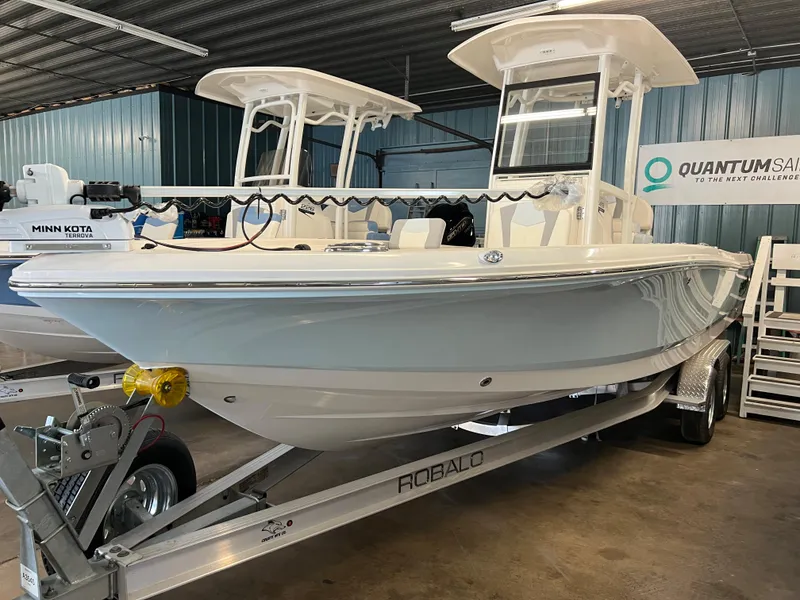 Slide: The Image of 2023 Robalo 246 Cayman boat on a trailer in a showroom. - 0