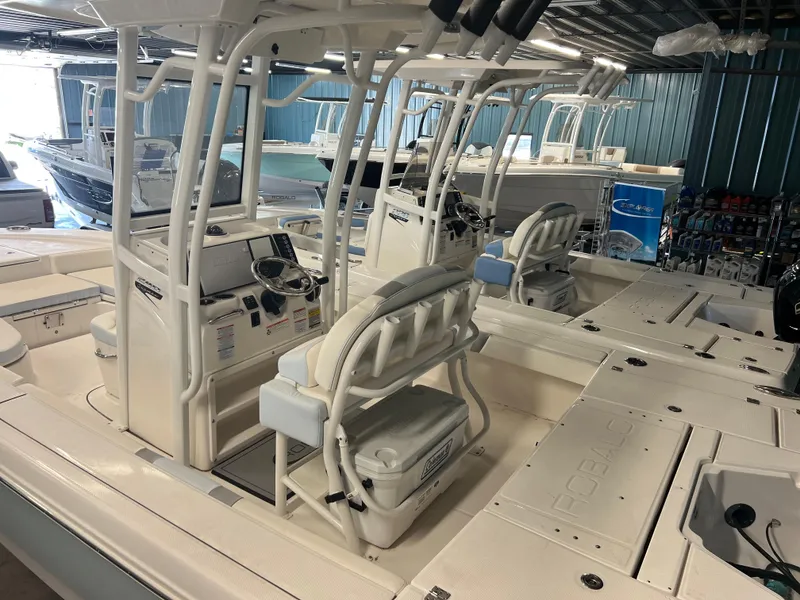 Slide: The Image of 2023 Robalo 246 Cayman boat interior with dual consoles and seating in a showroom. - 3