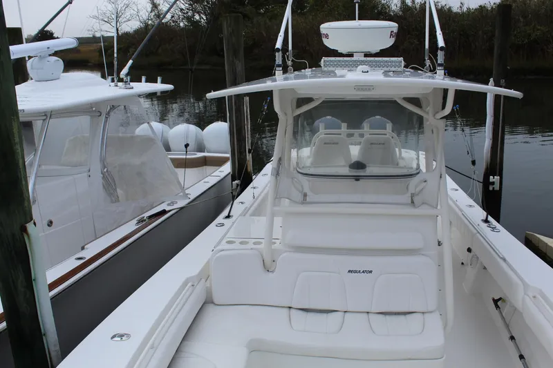 Slide: The Image of 2014 Regulator 34 SS boat docked, showcasing its sleek design and spacious seating. - 22