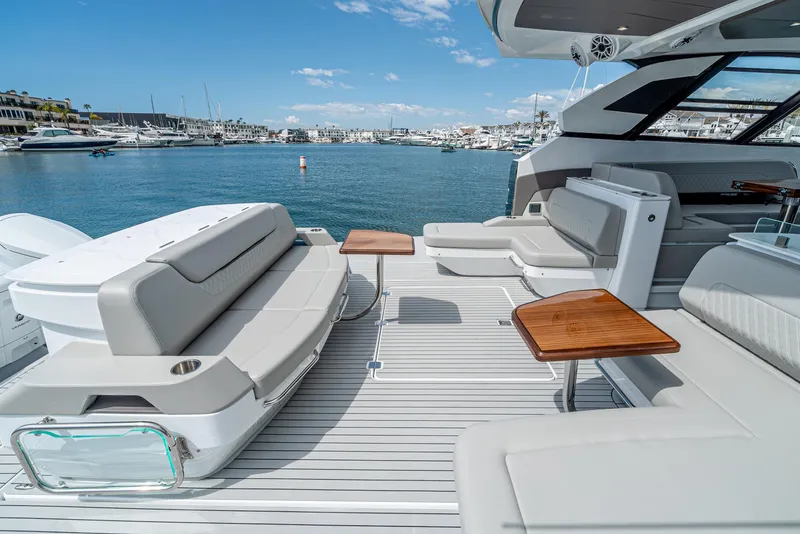 Slide: The Image of 2024 Cruisers Yachts 50 GLS luxury yacht deck with seating and tables, docked in a marina. - 29