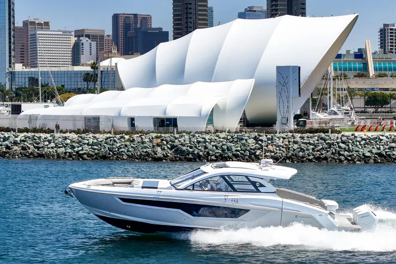 Slide: The Image of 2024 Cruisers Yachts 50 GLS cruising near modern waterfront architecture. - 3
