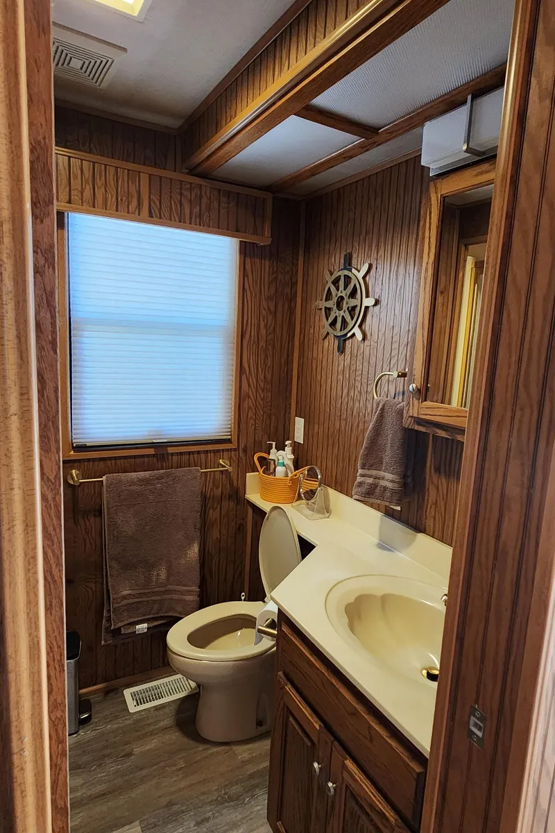 Slide: The Image of 1996 Sunstar 16x78 houseboat bathroom with wood paneling, sink, toilet, and nautical decor. - 38