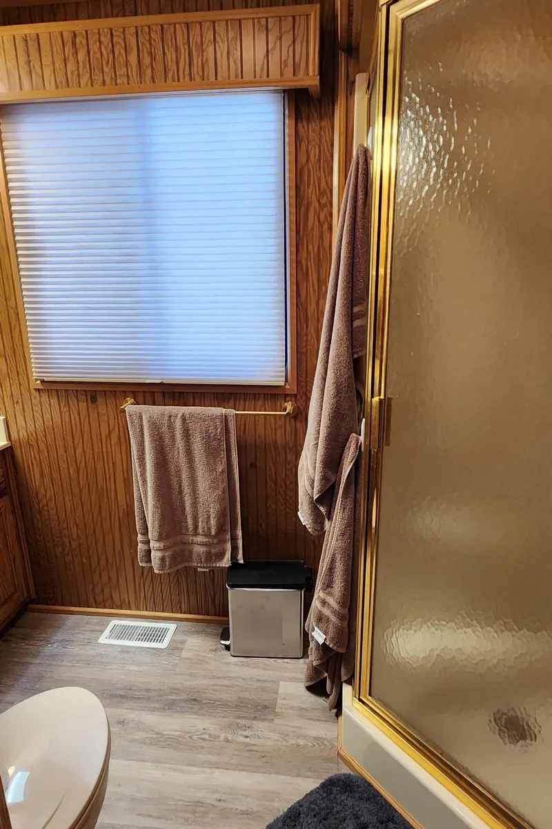Slide: The Image of Bathroom with wood paneling, shower, and towels in a 1996 Sunstar 16x78 houseboat. - 49