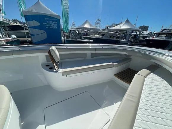 Slide: The Image of 2025 Mag Bay 43 Center Console boat interior at a marina with tents and boats in the background. - 34