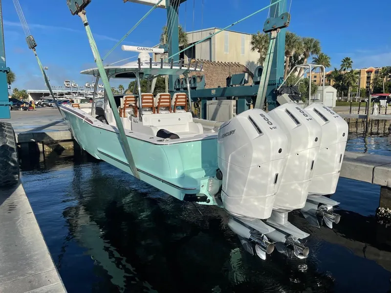 Slide: The Image of 2025 Mag Bay 43 Center Console boat with triple outboard engines being lowered into water. - 13