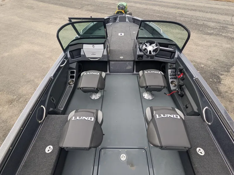 Slide: The Image of 2025 Lund 219 Pro V Fiberglass boat interior with seating and steering console. - 2
