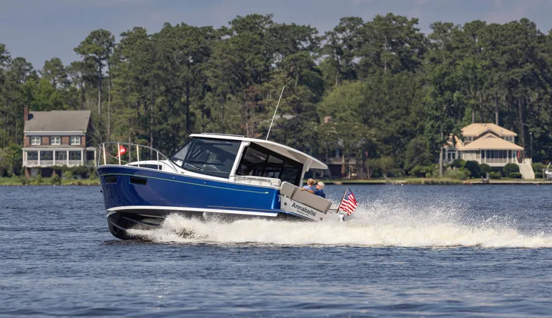 Slide: The Image of 2025 MJM 42 boat cruising on a lake with houses and trees in the background. - 10