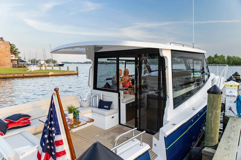 Slide: The Image of 2025 MJM 42 yacht docked by a scenic waterfront with American flag. - 15