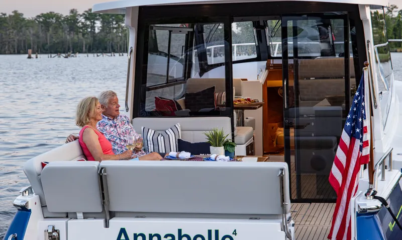 Slide: The Image of Couple relaxing on 2025 MJM 42 yacht, "Annabelle," with American flag, scenic water view. - 18