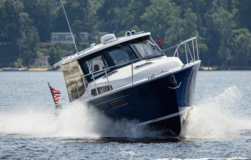 Slide: The Image of 2025 MJM 42 boat cruising on a lake with American flag, surrounded by trees. - 4