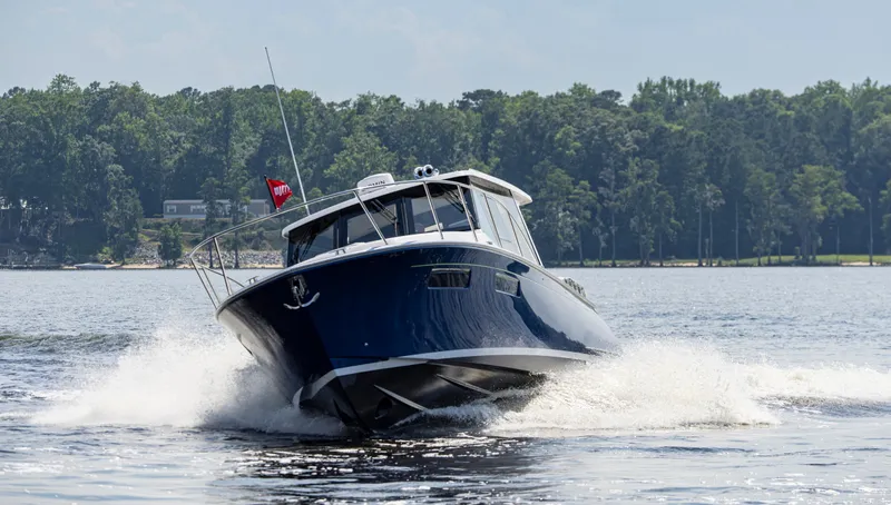 Slide: The Image of 2025 MJM 42 boat cruising on a lake with forested shoreline. - 7