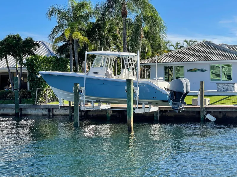 The Image of 2020 Cobia 301 Center Console boat docked by tropical house. - 0