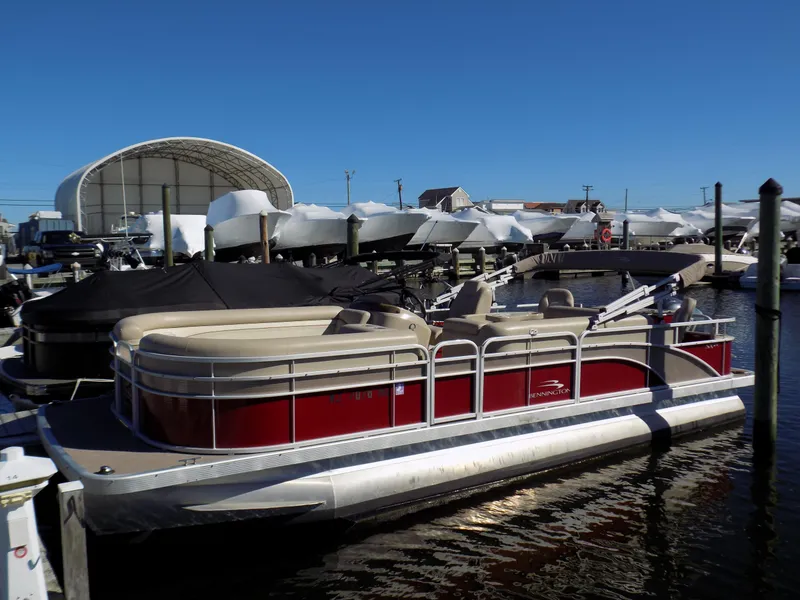 Slide: The Image of 2015 Bennington 24 SSX pontoon boat docked at a marina under clear blue skies. - 0