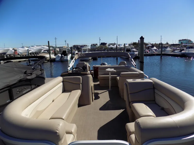 Slide: The Image of 2015 Bennington 24 SSX pontoon boat with spacious seating at a marina. - 2