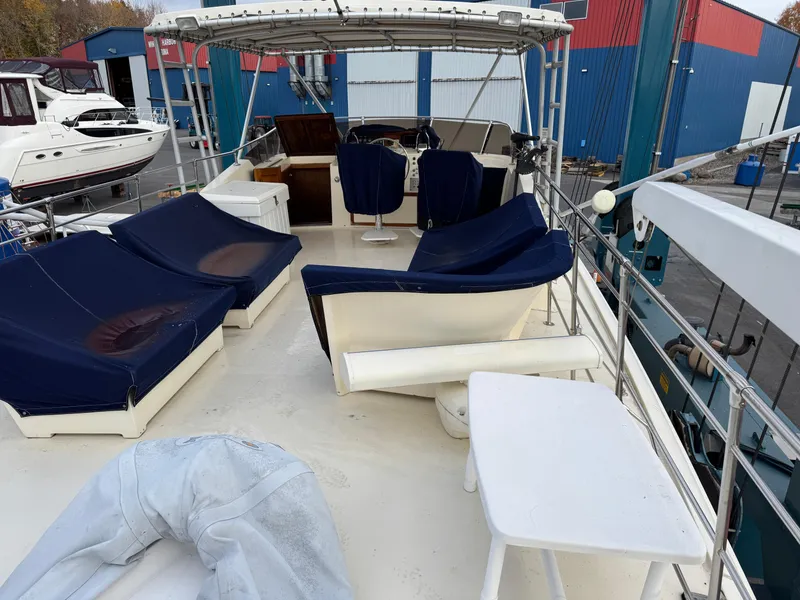 Slide: The Image of 1978 Hatteras 58 MY yacht deck with seating and table, docked near other boats. - 12