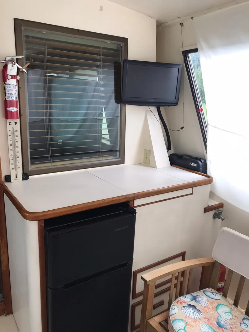 Slide: The Image of 1978 Hatteras 58 MY interior with TV, mini-fridge, and seating area. - 23
