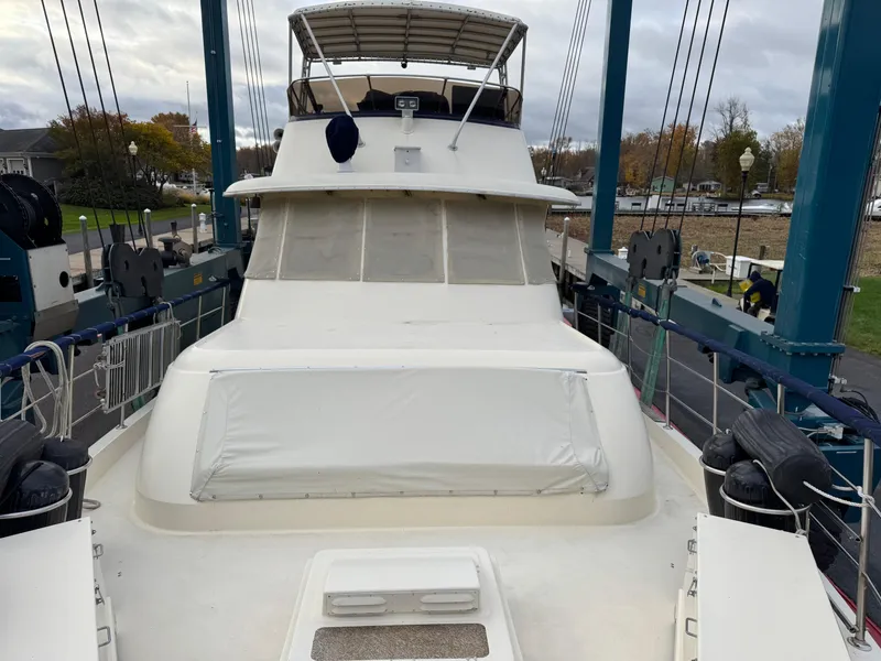 Slide: The Image of 1978 Hatteras 58 MY yacht on a lift, showcasing its spacious deck and flybridge. - 4
