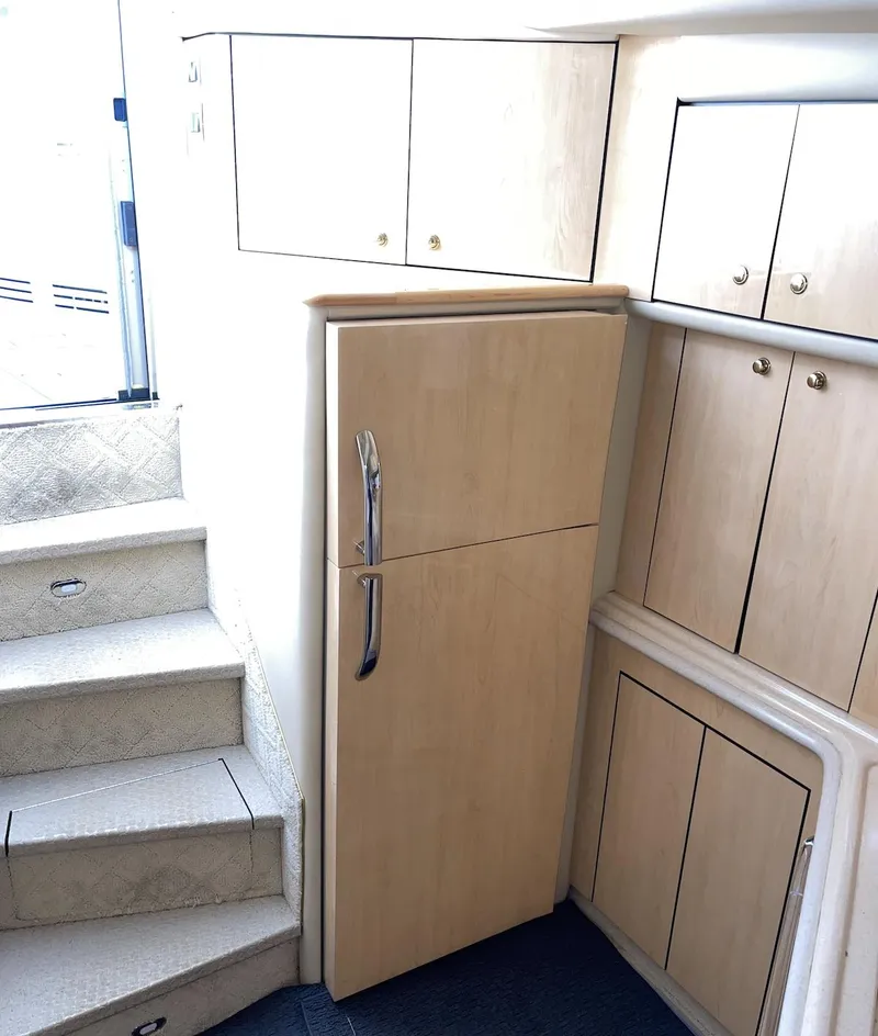 Slide: The Image of 2000 Sea Ray 540 Sundancer interior with wooden cabinets and refrigerator. - 13