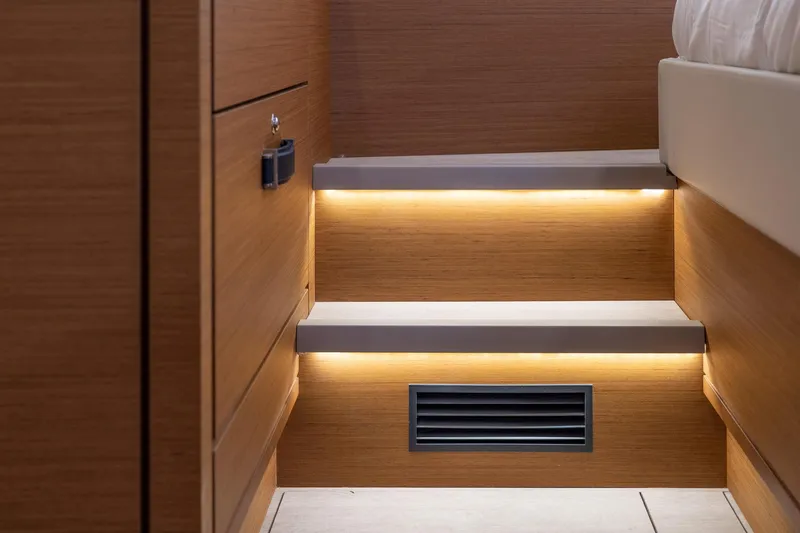 Slide: The Image of 2023 Jeanneau 65 yacht interior with illuminated wooden steps and modern design. - 23