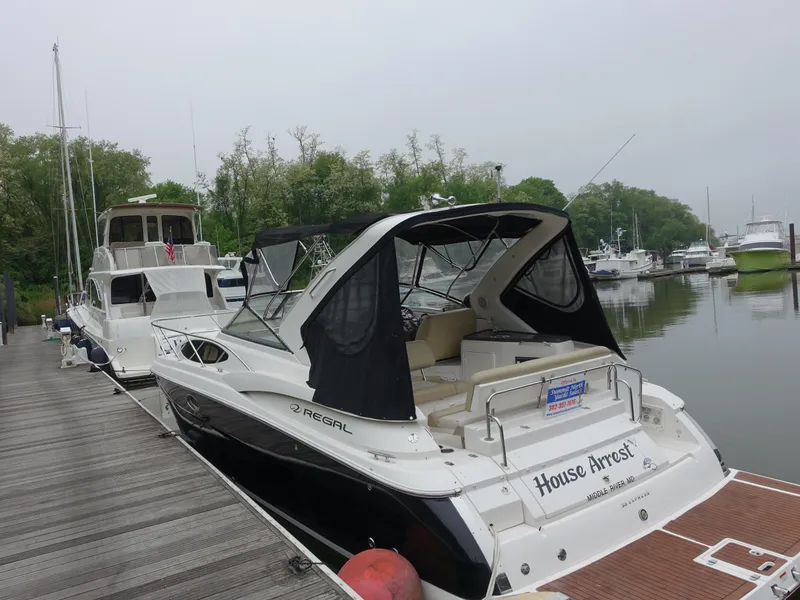 The Image of 2011 Regal 35 Express Cruiser docked at marina, surrounded by trees and other boats. - 1
