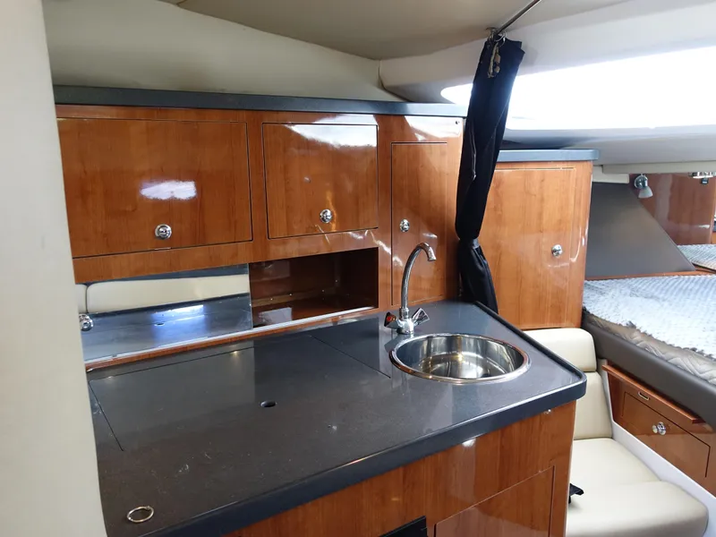 Slide: The Image of 2011 Regal 35 Express Cruiser interior with wooden cabinets and compact kitchenette. - 11