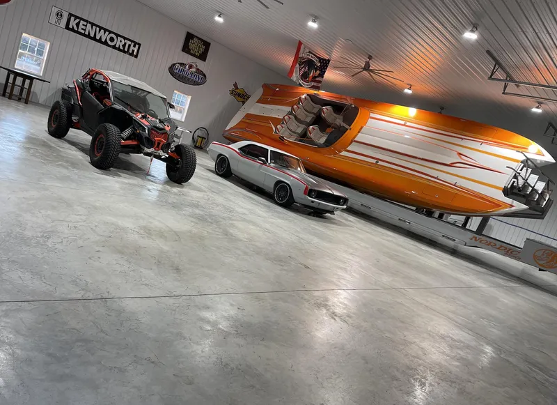 Slide: The Image of 2017 Nordic 43' Enforcer boat, off-road vehicle, and classic car in a spacious garage. - 11