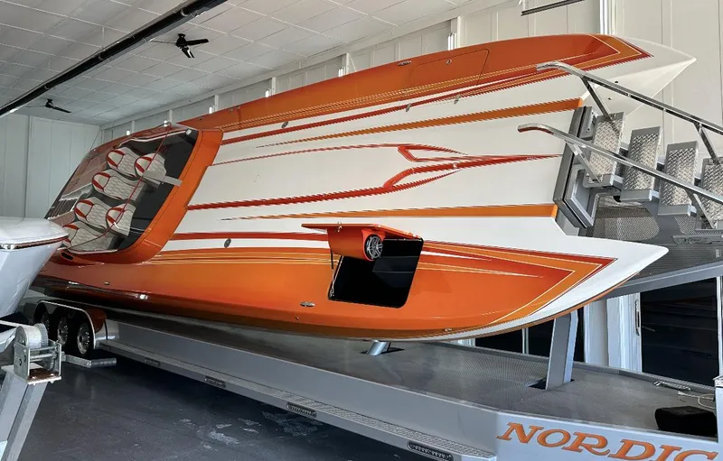 Slide: The Image of 2017 Nordic 43' Enforcer boat with orange and white design on a trailer. - 2