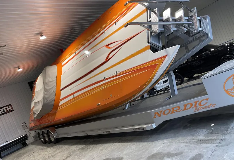 Slide: The Image of 2017 Nordic 43' Enforcer boat in storage, orange and white design, on a trailer. - 22