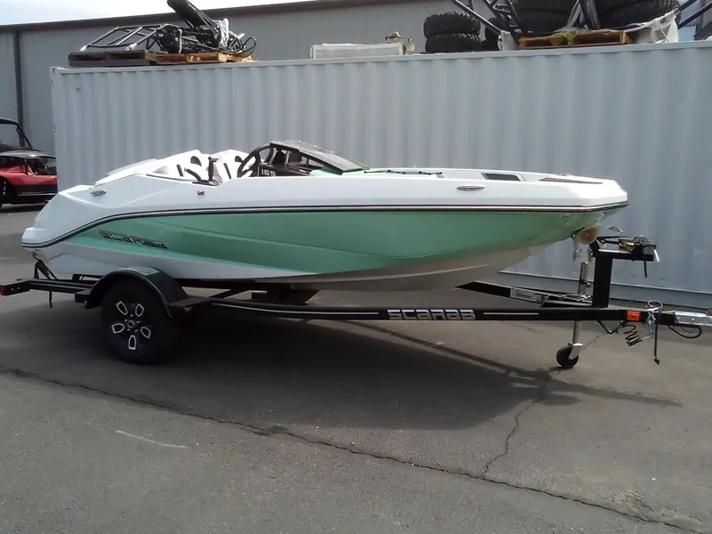 Slide: The Image of 2023 Scarab 165 ID boat on a trailer, white and green hull, parked outdoors. - 3