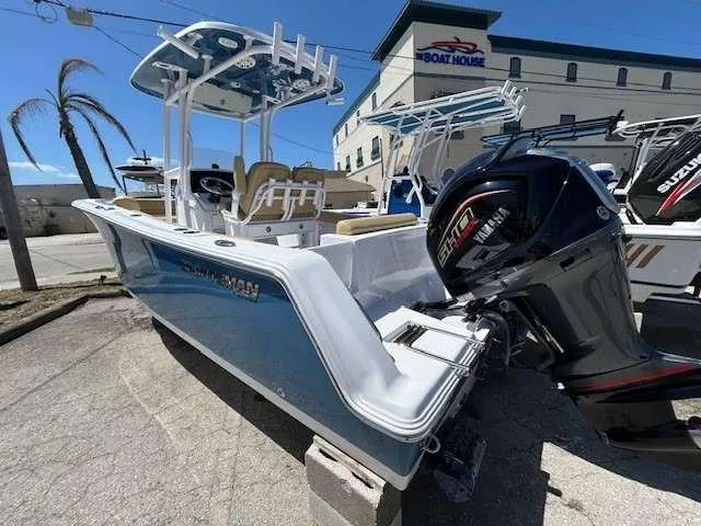 Slide: The Image of 2023 Sportsman 232 Open boat with Suzuki engine, displayed outdoors near a boathouse. - 12