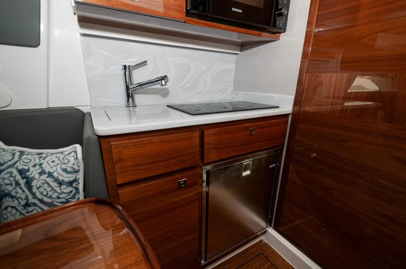 Slide: The Image of 2022 Valhalla Boatworks V46 Center Console interior kitchen with sink, stove, and wooden cabinetry. - 10