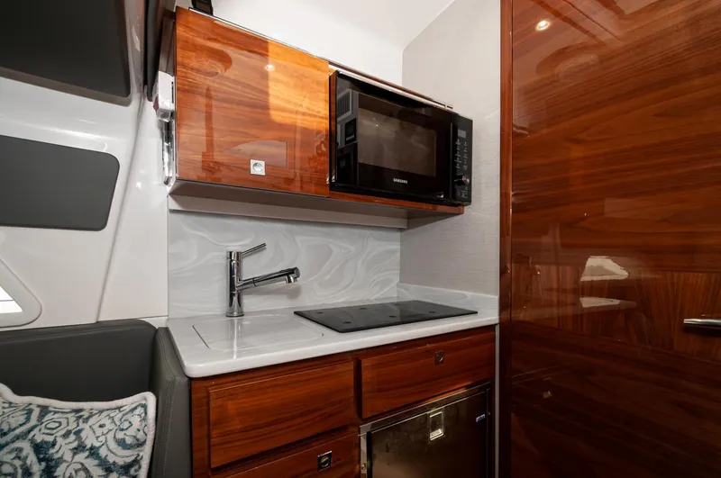 Slide: The Image of 2022 Valhalla Boatworks V46 Center Console kitchen with microwave and modern wood cabinetry. - 8