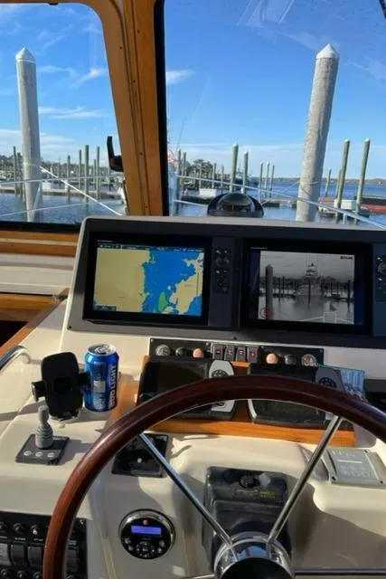 Slide: The Image of Helm of 2006 Sabre 38 Hard Top Express with navigation screens and marina view. - 2