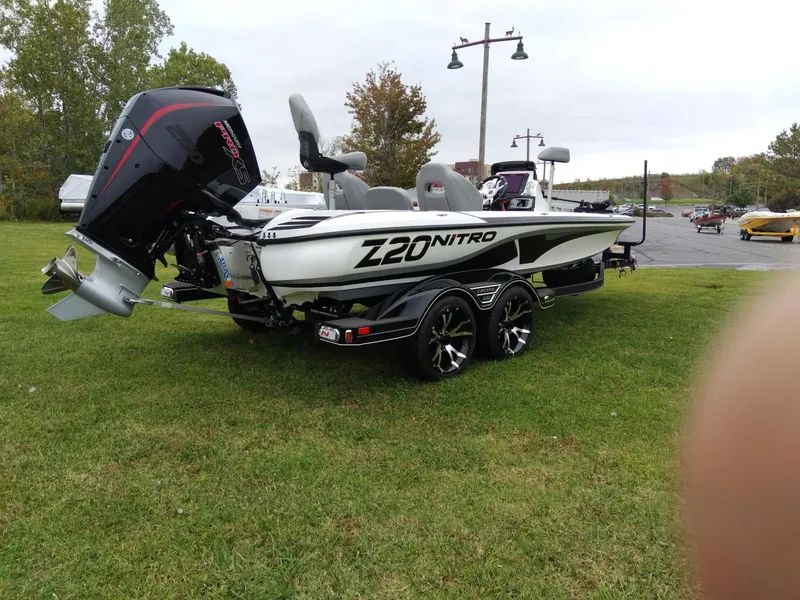 Slide: The Image of 2023 Nitro Z20 boat on grass with outboard motor and trailer. - 2