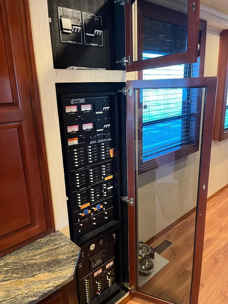 Slide: The Image of Electrical control panel inside a 2009 Fantasy Houseboat with wooden cabinetry and glass door. - 14