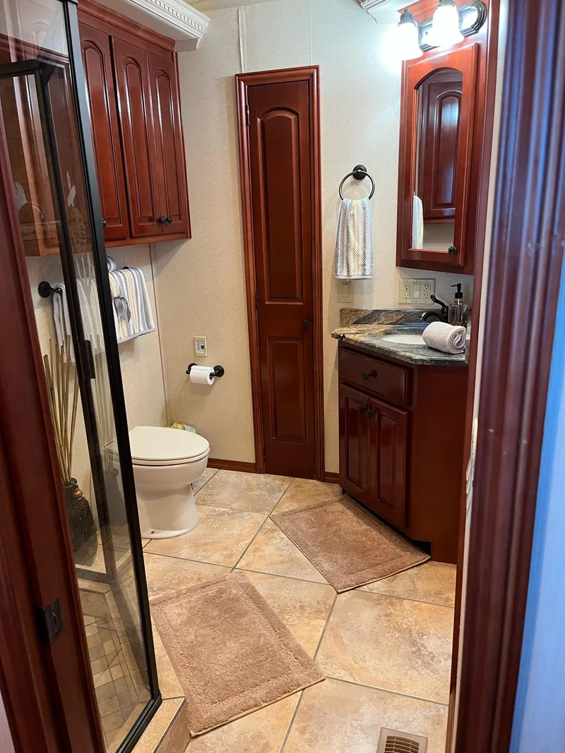 Slide: The Image of 2009 Fantasy Houseboat bathroom with wooden cabinets, tiled floor, and glass shower. - 16
