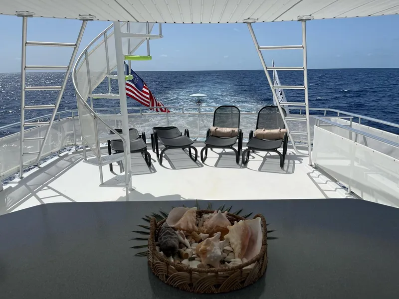 Slide: The Image of 2009 Fantasy Houseboat deck with ocean view, lounge chairs, and seashell centerpiece. - 23