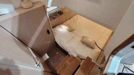 Slide: The Image of 2024 Jeanneau 55 interior cabin with cozy bed and wooden steps. - 17