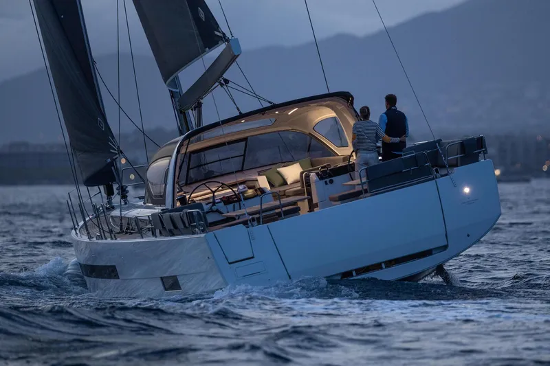 Slide: The Image of 2024 Jeanneau 55 yacht sailing at dusk with two people on deck. - 2