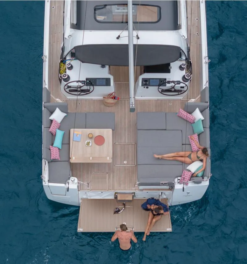 Slide: The Image of 2024 Jeanneau 55 yacht with spacious deck, lounging area, and people enjoying the water. - 4