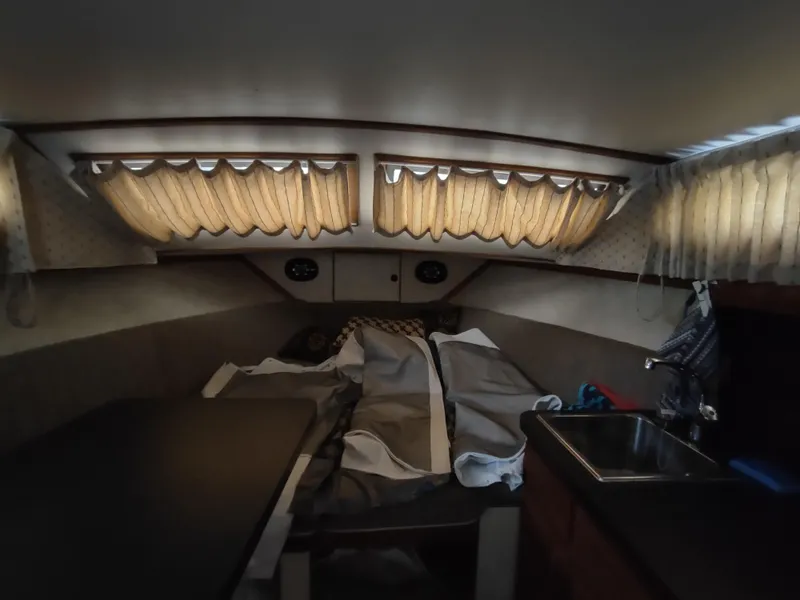 Slide: The Image of 1976 Trojan 260 Hardtop Express cabin interior with bed, curtains, and small sink. - 22