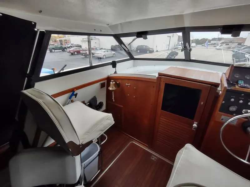 Slide: The Image of 1976 Trojan 260 Hardtop Express boat interior with helm, seating, and wooden cabinetry. - 4