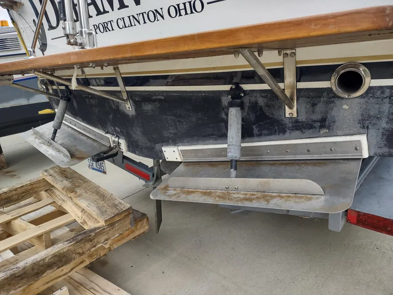 Slide: The Image of 1976 Trojan 260 Hardtop Express boat stern with trim tabs and wooden pallet nearby. - 23