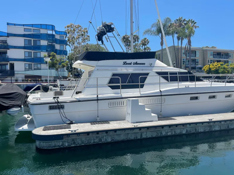 The Image of 1986 Sea Hawk Sedan boat docked in marina with modern buildings in background. - 0